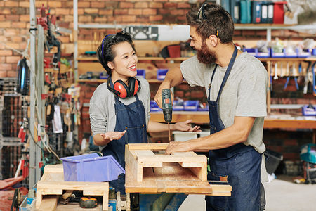 Smiling female carpenter talking to her coworker drilling screws when making wooden drawer Schlagwort(e): Men, Working, People, Occupation, Workshop, Create, Industry, Carpenter, Manual Worker, Male, Female, Box, Standing, Smiling, Skill, Teamwork, Young Adult, Small Business, Caucasian Ethnicity, Wireless Building - Activity, Manufacturing, Carpentry, Craftsperson, Expertise, onstruction Worker, Young Men, Craft, Happiness, Place of Work, Confidence, Equipment, Wood - Material, Work Tool, Coworker, Professional Occupation, Women, Factory, Creativity, Designl, woman, woodwork, job, assembling, drawer, stand, apprentice, helping, positive, Asian, Vietnamese, men, working, people, occupation, workshop, create, industry, carpenter, manual worker, male, female, box, standing, smiling, skill, teamwork, young adult, small business, caucasian ethnicity, wireless building - activity, manufacturing, carpentry, craftsperson, expertise, onstruction worker, young men, craft, happiness, place of work, confidence, equipment, wood - material, work tool, coworker, professional occupation, women, factory, creativity, designl, woman, woodwork, job, assembling, drawer, stand, apprentice, helping, positive, asian, vietnamese