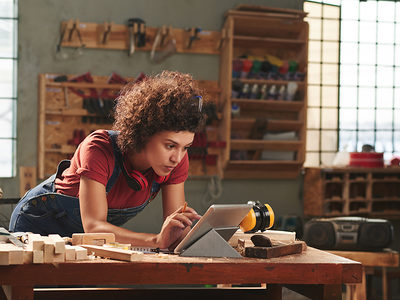 Young concentrated woman with curly hair reading instructions on digital tablet before working with wood Schlagwort(e): woman, female, young, attractive, curly, concentrated, digital, tablet, technology, internet, leaning, table, looking, reading, wifi, carpentry, joinery, timber, wood, wooden, plank, tool, skill, manual, equipment, professional, craft, craftsman, handyman, occupation, working, woodworking, workshop, woman, female, young, attractive, curly, concentrated, digital, tablet, technology, internet, leaning, table, looking, reading, wifi, carpentry, joinery, timber, wood, wooden, plank, tool, skill, manual, equipment, professional, craft, craftsman, handyman, occupation, working, woodworking, workshop