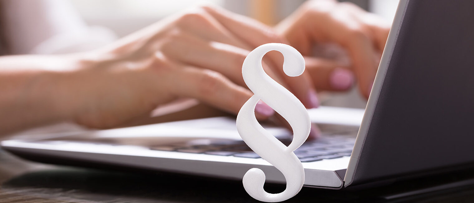 Close-up Of A White Paragraph Symbol In Front Of Businesswoman Working On Laptop Schlagwort(e): laptop, paragraph, hand, white, type, working, woman, keyboard, using, symbol, close-up, piracy, legal, law, hands, sign, open, data, people, desk