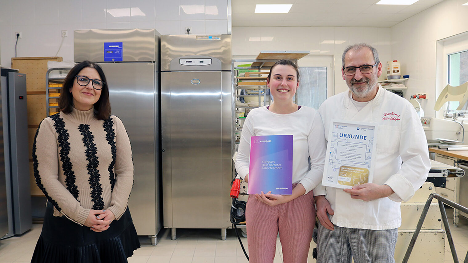 Mobilitätsberaterin Francesca Venturella (l.) überreicht Lara Fabienne Schäfer (Mitte) den "Europass" als Nachweis für ihr Praktikum in Südtirol sowie Betriebsinhaber Felix Schäfer (r.) die Urkunde für das entsendende Unternehmen.