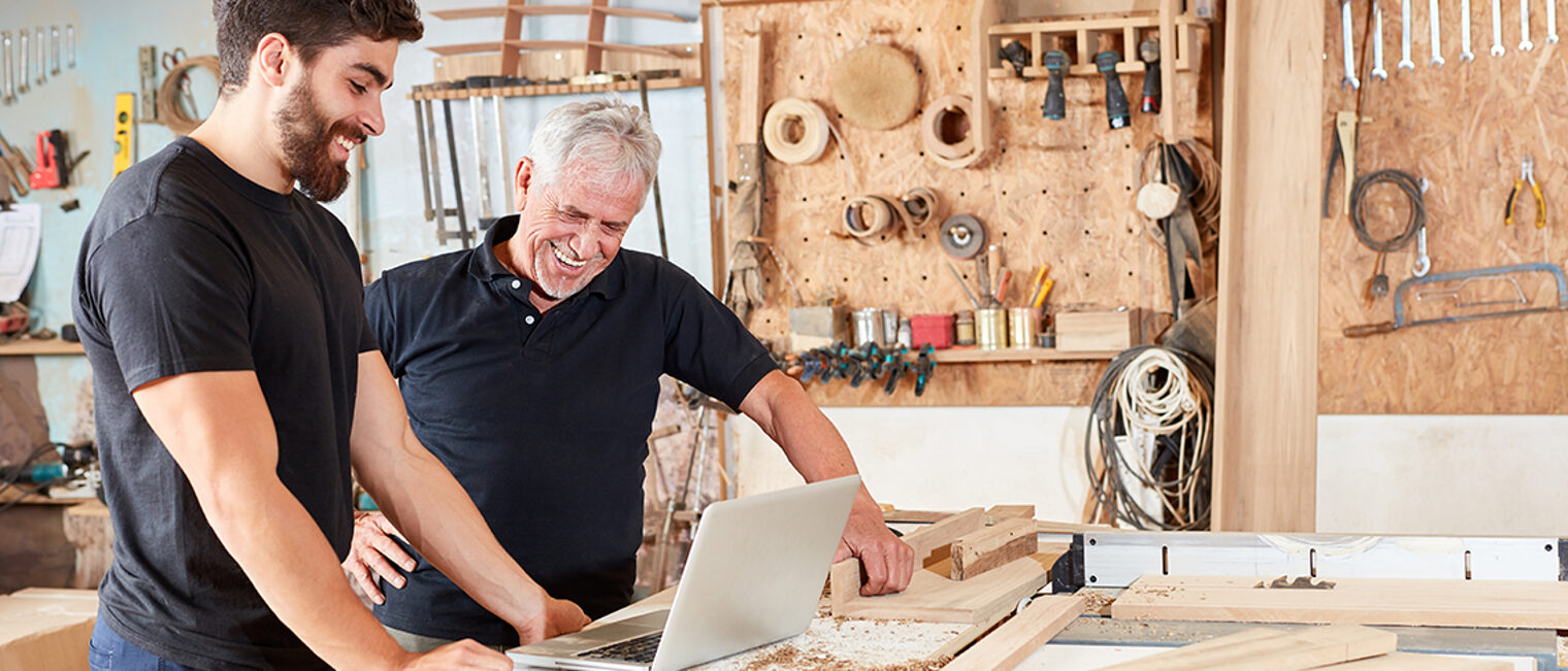 Senior und Handwerker Lehrling zusammen am Laptop Computer in der Werkstatt Schlagwort(e): Schreinerei, Handwerker, Laptop, Computer, online, Internet, Werkstatt, Email, Auftrag, Bestellung, Freude, glücklich, Webseite, digital, Technologie, Verbindung, Senior, Schreiner, Tischler, Planung, Tischlerei, Mann, Holz, Holzarbeit, Bauplan, Handwerk, Zimmerei, Arbeit, Beruf, Bau, Werkzeug, Arbeiter, Holzarbeiter, Industrie, Holzverarbeitung, arbeiten, Leute