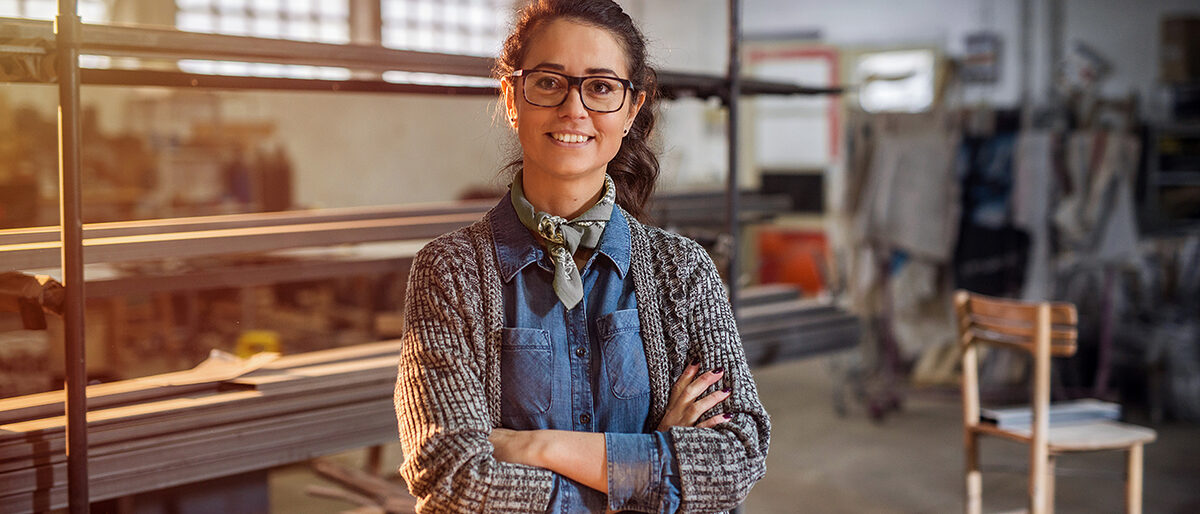 Strong confident middle aged woman engineer standing and looking at the camera at her workshop. Schlagwort(e): store, storehouse, portrait, online, worker, service, equipment, work, owner, designer, caucasian, industry, internet, occupation, digital, female, craft, business, technology, aged, metal, technician, workshop, computer, pretty, factory, smiling, notebook, engineer, industrial, mobile, steel, pad, manager, creative, tablet, people, happy, professional, repair, working, carpenter, young, check, wooden, job, design, woman