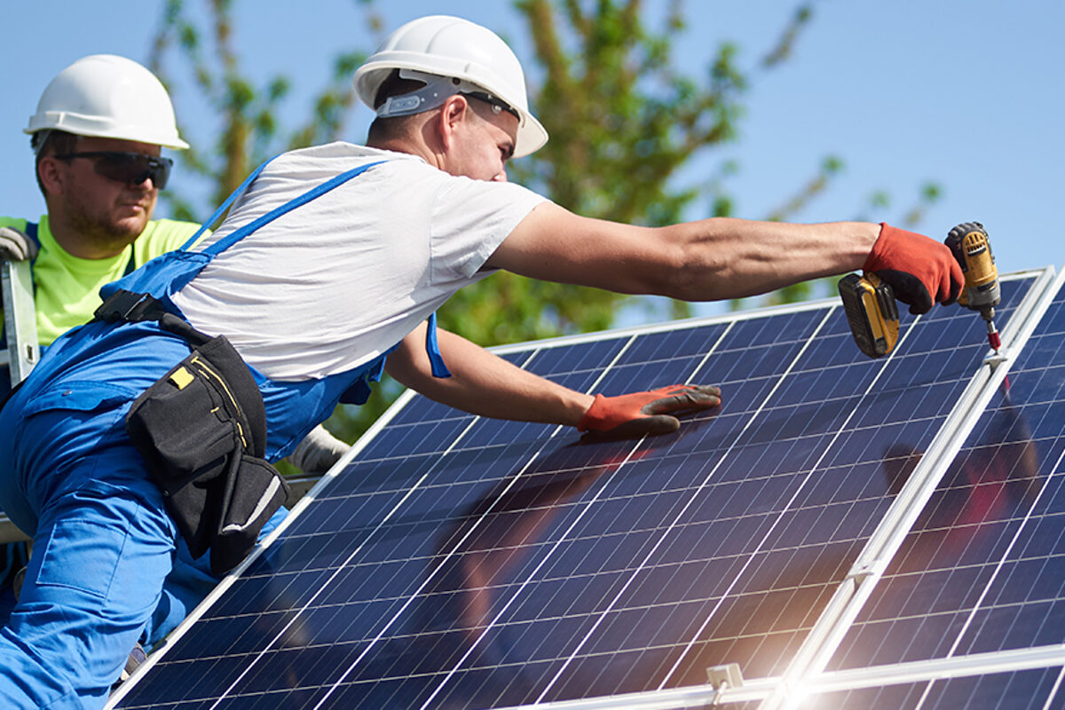Two workers technicians installing heavy solar photo voltaic panels to high steel platform. Exterior solar system installation, alternative renewable green energy generation concept. Schlagwort(e): system, solar, power, energy, panels, technology, installation, exterior, renewable, alternative, generator, photovoltaic, install, mounting, maintenance, supply, environmental, eco, green, electrical, generation, building, ecological, electric, construction, worker, technician, installer, engineer, professional, men, team, electricity, light, economy, modern, resource, module, background, blue, screwdriver, hight, recycling, structure, cells, texture, price, investment, assemble, eco friendly