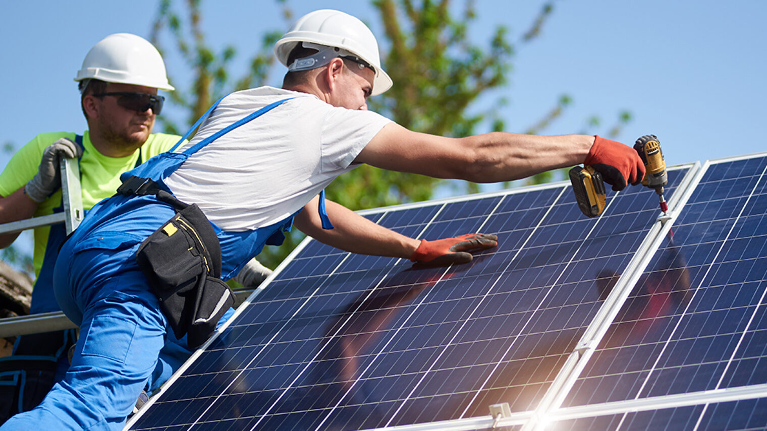 Two workers technicians installing heavy solar photo voltaic panels to high steel platform. Exterior solar system installation, alternative renewable green energy generation concept. Schlagwort(e): system, solar, power, energy, panels, technology, installation, exterior, renewable, alternative, generator, photovoltaic, install, mounting, maintenance, supply, environmental, eco, green, electrical, generation, building, ecological, electric, construction, worker, technician, installer, engineer, professional, men, team, electricity, light, economy, modern, resource, module, background, blue, screwdriver, hight, recycling, structure, cells, texture, price, investment, assemble, eco friendly