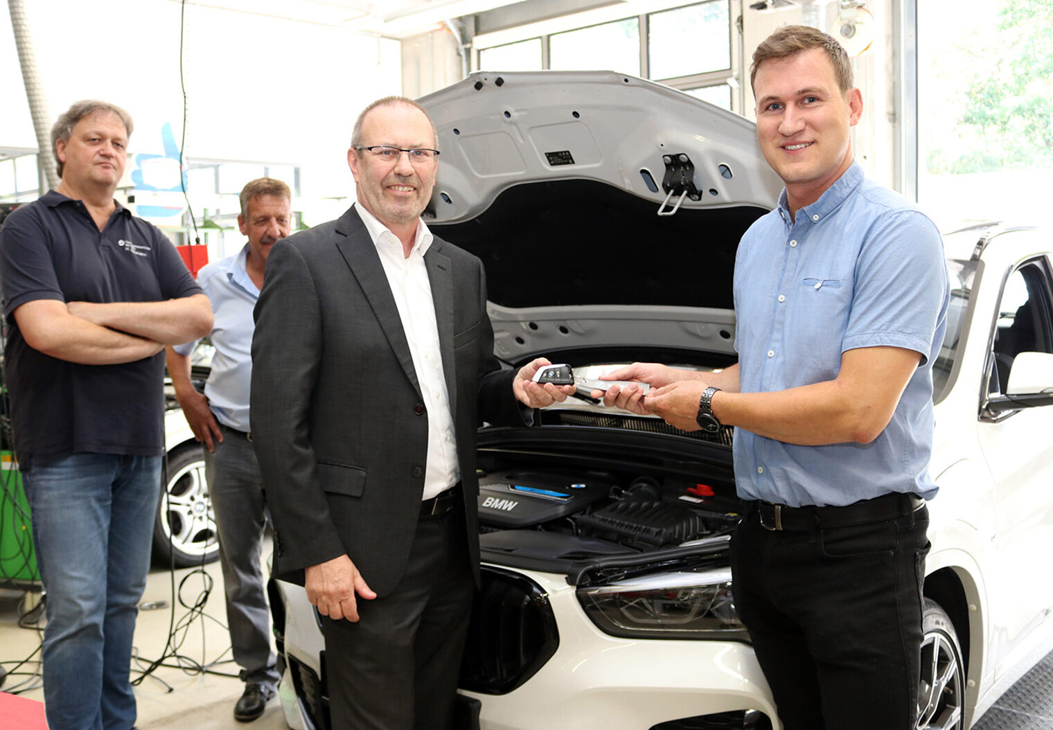 Bernd Kiefer, Manager Kundensupport der BMW AG (Mitte) übergibt den Autoschlüssel an den Leiter des BTZ der Handwerkskammer der Pfalz, Steffen Kluge (r.)