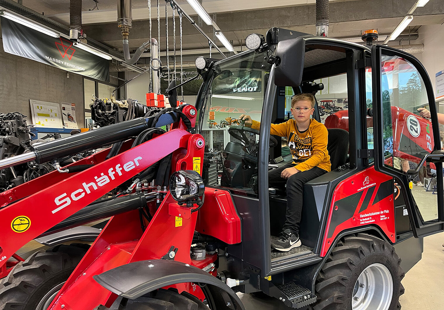 Junger Besucher auf dem E-Radlader in der Werkstatt der Land- und Baumaschinenmechatroniker